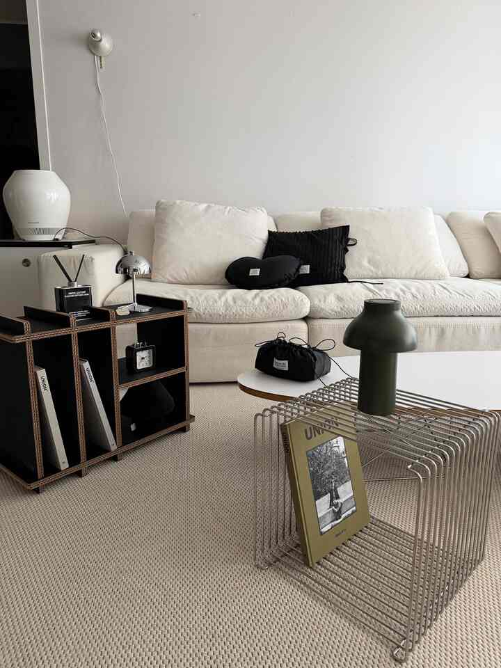 Modern living room with white walls and sofa as focal points, black fabric cushions and small coffee table creating a cozy atmosphere