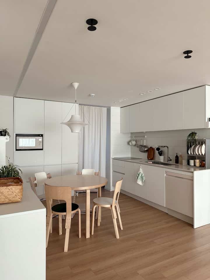 白と木目調が調和したモダンなキッチン、丸いダイニングテーブルと椅子が配置された4人暮らしに適した居心地の良い空間