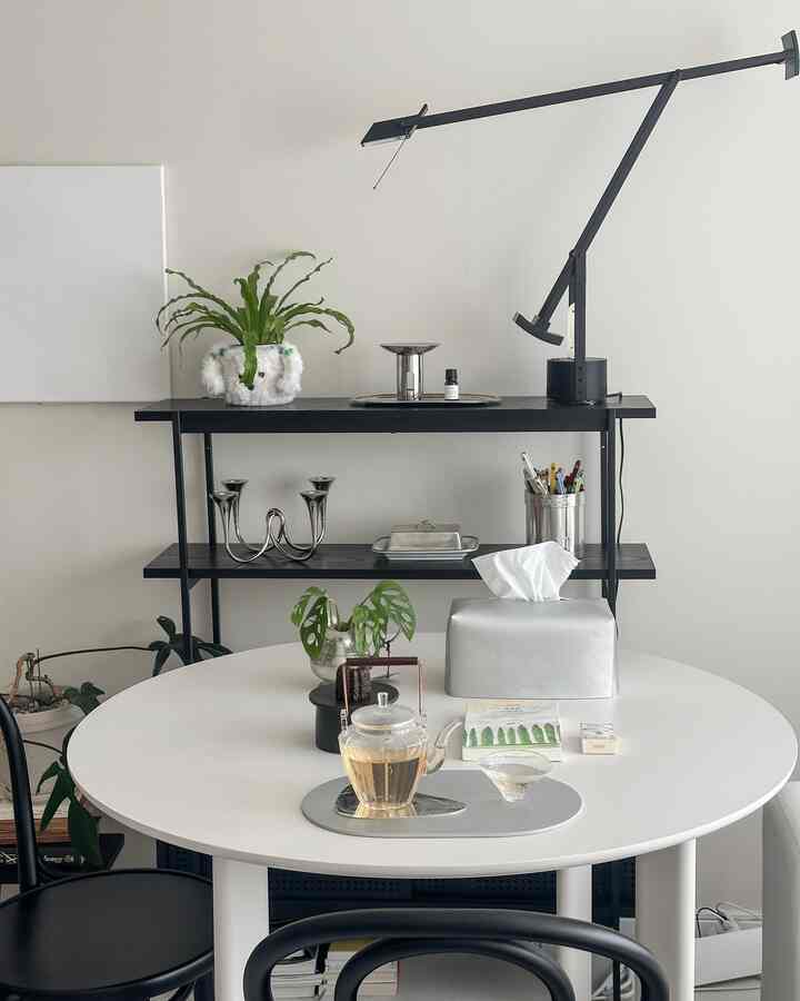白と黒のトーンのリビング、丸テーブルと棚、テーブルランプが配置されたシンプルでモダンな印象的な空間