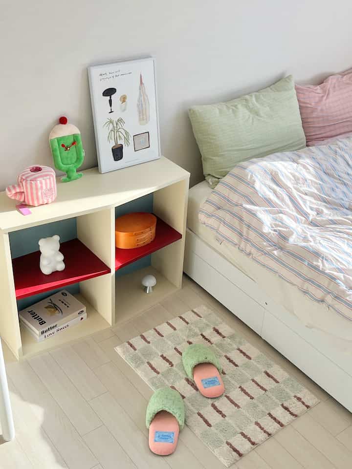 パステルカラーと白が調和した、収納棚と寝具が配された雰囲気のあるミニマルな寝室