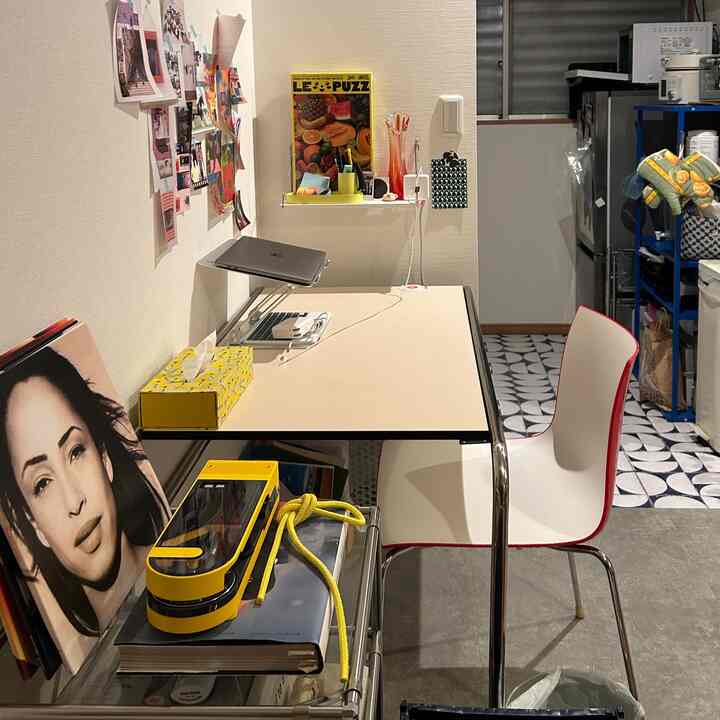 イエローアクセントのコンパクトなホームオフィスとキッチンスペース、デスクとオフィスチェアが配置された実用的なインテリア