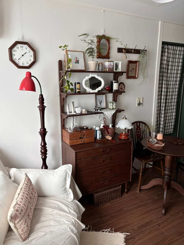 木目調と白が調和するヴィンテージ風のダイニングルーム。ソファやテーブル、壁の棚に植物が配置された雰囲気のある空間