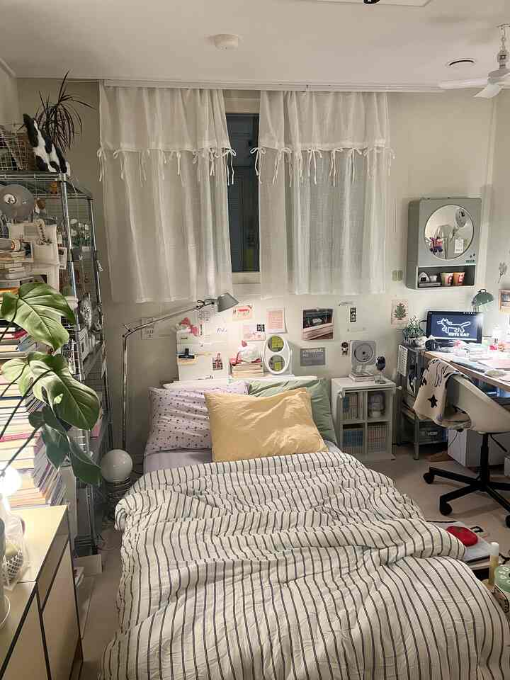 白とナチュラルカラーが調和した狭い寝室、ベッドとデスク、本棚が配置された雰囲気のあるインテリア