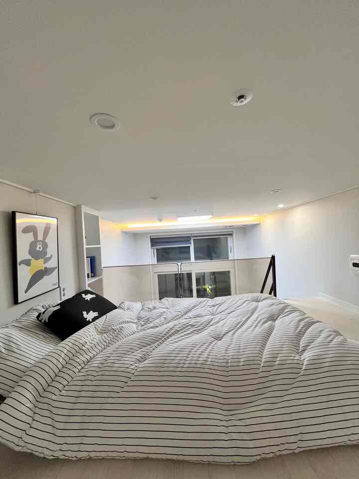 White and black tone loft bedroom featuring bunny artwork and striped duvet cover in a clean, cozy space