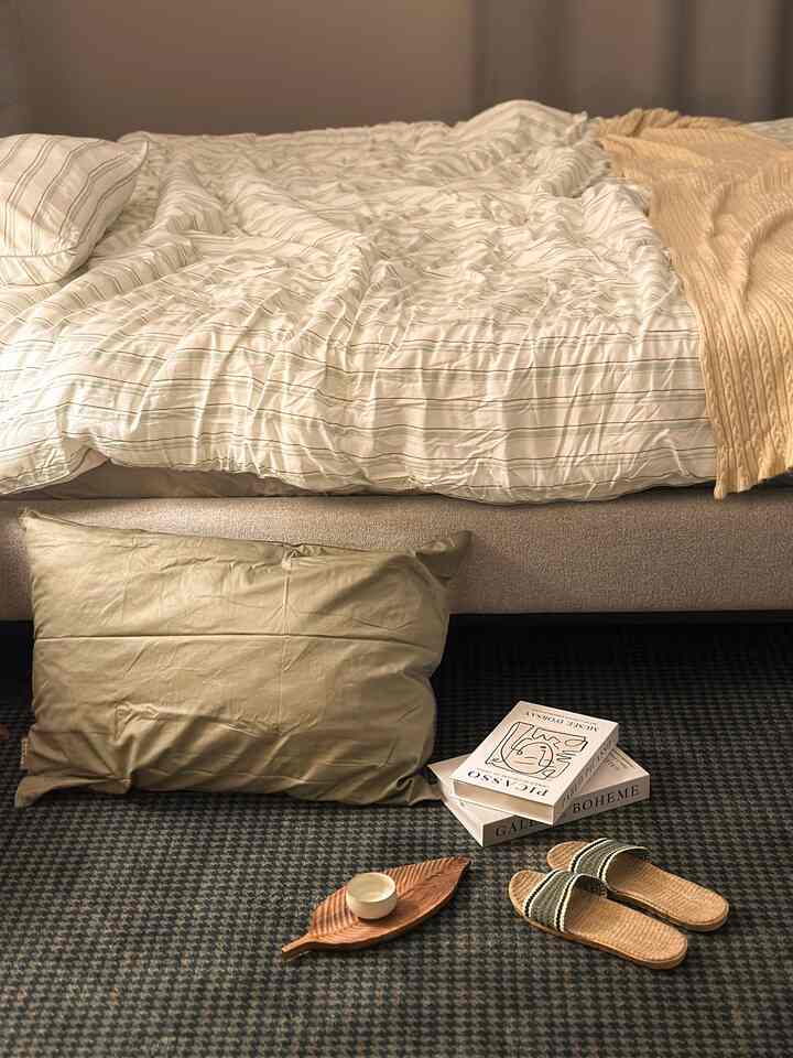 ナチュラルなベージュとホワイトの寝室、枕とラグが配置された落ち着いた雰囲気のインテリア