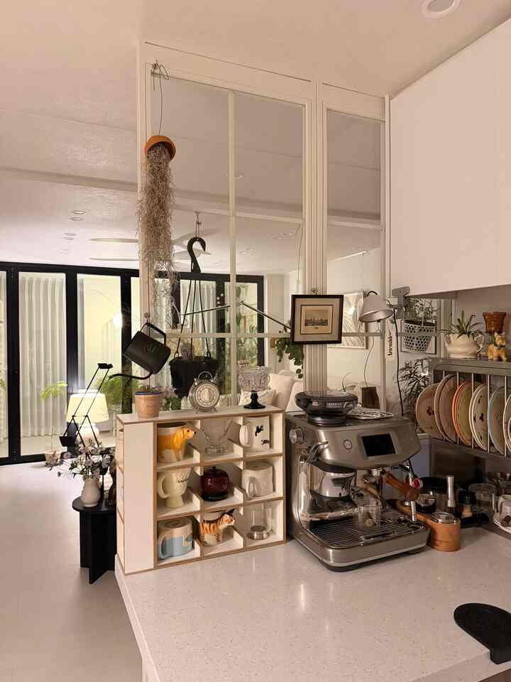 白とシルバーのトーンのモダンなキッチン、エスプレッソマシンと収納棚が配置された雰囲気のあるホームカフェ空間