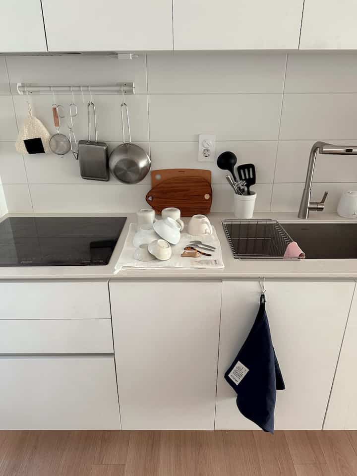 白と木目調のキッチンスペース、シンクや調理器具がすっきりと配置されたミニマルな雰囲気のインテリア