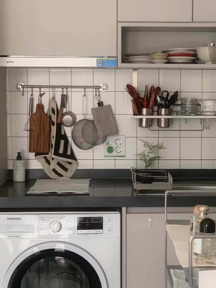 白とグレーの色調が特徴のキッチン、整理された調理器具と食器が配置された雰囲気のあるモダンな空間