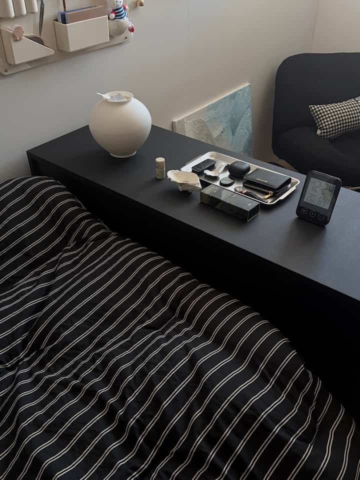 Black and white toned bedroom featuring striped bedding and modern furniture arranged neatly