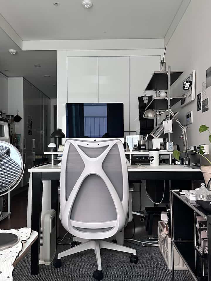 ホワイトとブラックのトーンでまとめられたモダンなホームオフィス、コンパクトな部屋にパソコンとオフィスチェアが配置されたインテリア