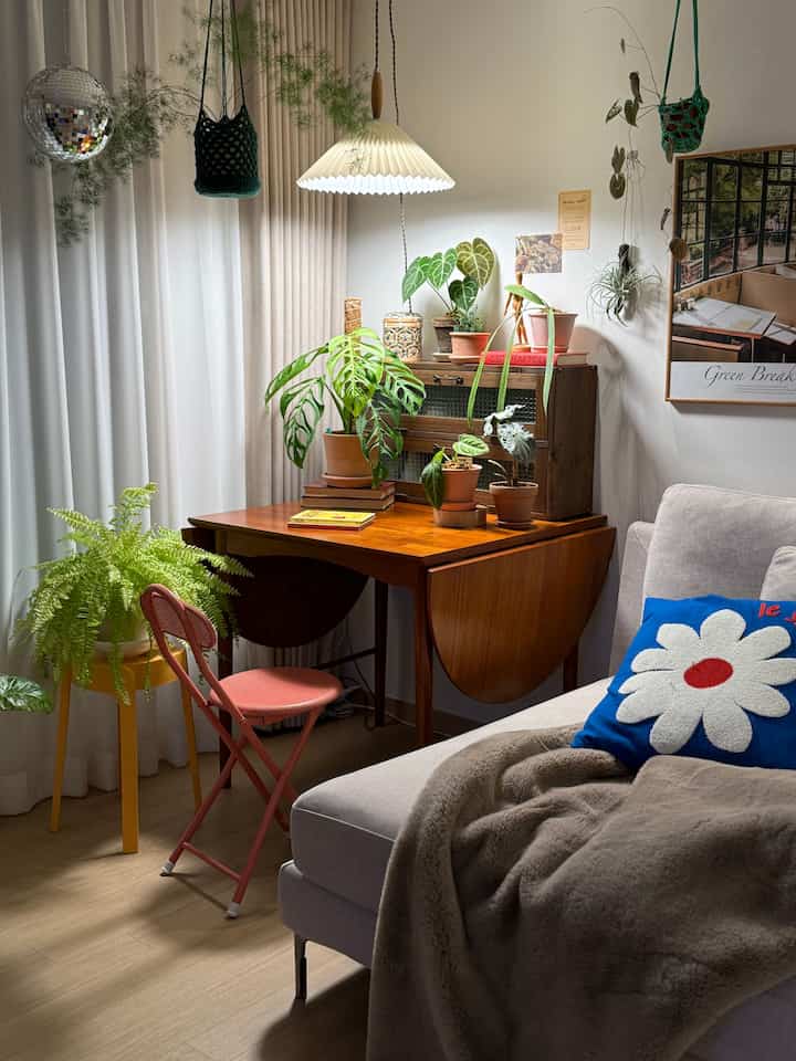 ウッドトーンのナチュラルなリビング、植物とペンダントライト、快適な寝具が配置された温かみのある空間