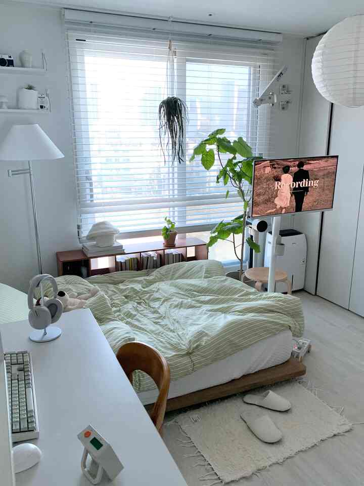 Compact single household bedroom with home office setup featuring white and wood tones, large window with blinds creates bright atmosphere