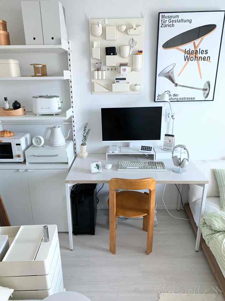White-toned compact remote work space featuring an organized desk and kitchen appliances in a clean home office