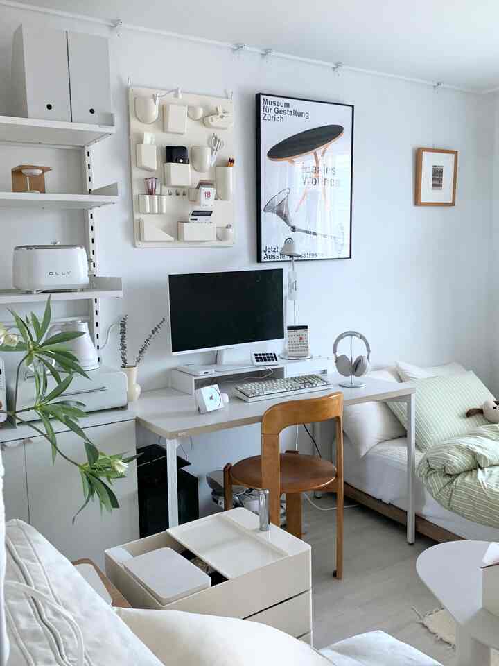 White and wood-toned studio apartment bedroom with home office setup, featuring a clean and simple modern atmosphere