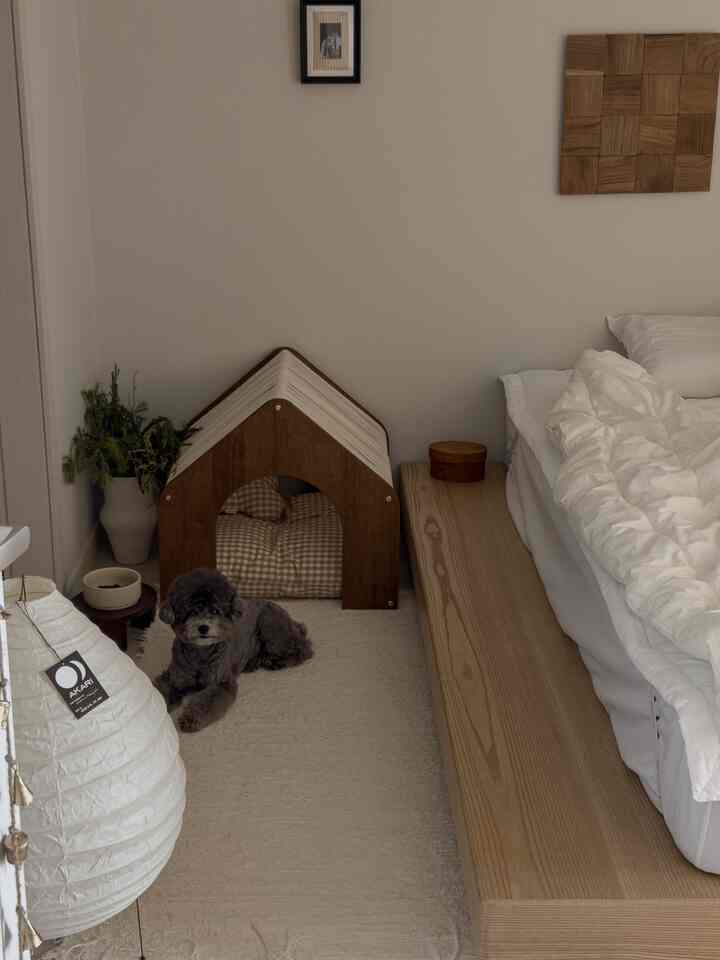 自然な木目調とベージュの寝室、低い木製ベッドと犬の家が配置された雰囲気のあるインテリア