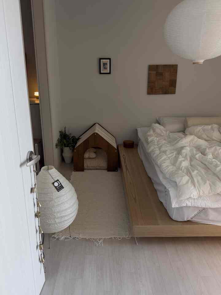 ベージュと白のトーンの寝室、ローベッドとペットハウスが配置されたナチュラルな雰囲気のインテリア