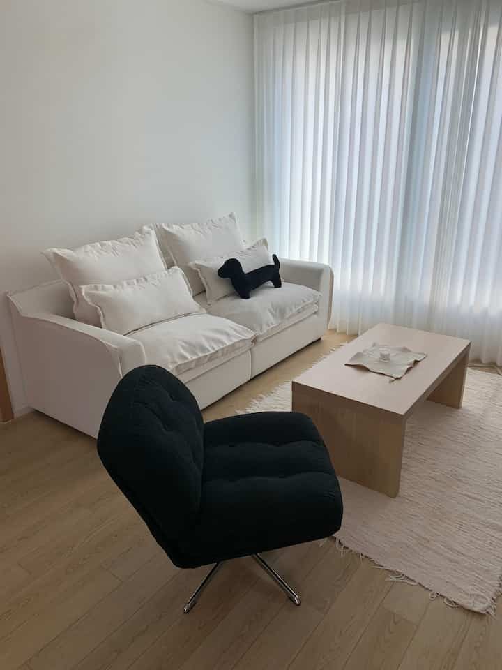 白と黒のトーンでまとめられたナチュラルモダンなリビング、快適なソファとアームチェアが配置された印象的な空間