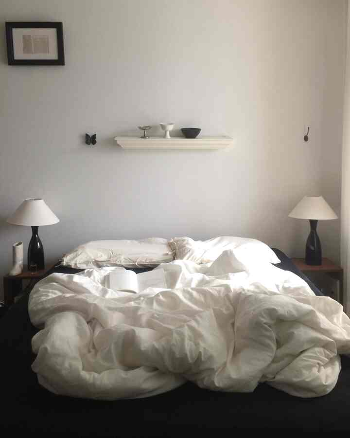 白黒のモノトーンの寝室、中央にベッドと寝具が配置されたシンプルでモダンな印象的な空間