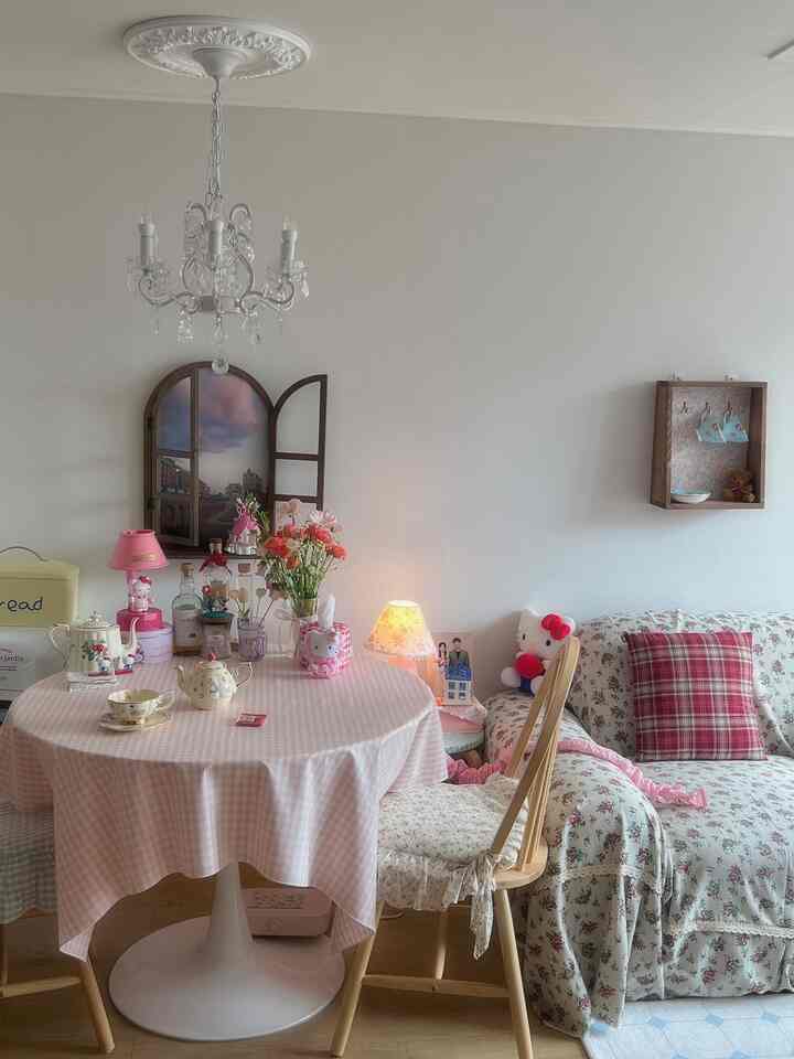 ピンク色調と花柄が印象的なリビング、丸テーブルや花、シャンデリアが配置された雰囲気のある空間