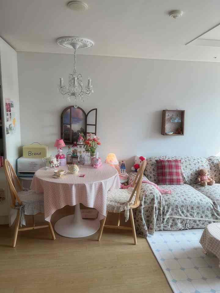 ピンクとナチュラルカラーの調和がとれたダイニング、花柄ソファとギンガムチェックのテーブルクロスが印象的な空間