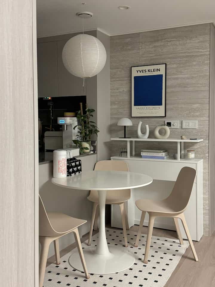 White and gray toned kitchen dining space featuring a mid-century modern poster and pendant lamp with clean interior style