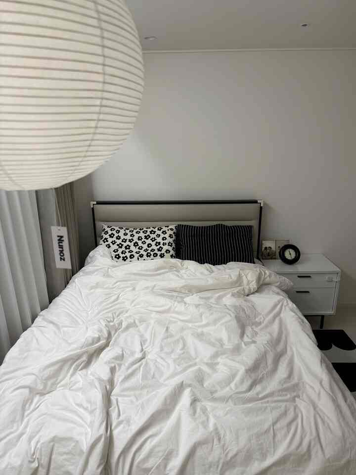 I kept the master bedroom as empty as possible and decorated it to focus solely on sleep.

With white bedding as the base,
and black accents on cushions and accessories,
I created a calming yet not-so-boring atmosphere.

For the lighting, I chose the famous Nunoz brand.

I chose a mobile type,
and hung a wireless LED mood light.

I can turn it on and off with a remote control while lying down,
which is much more convenient and satisfying than I expected.

A single light can completely change the mood of the space.

Since this is where I end my day,
I think comfort is the most important thing.

Decoration is kept to a minimum,
and this is where I spend the most time.

#MasterBedroomInterior #침실인테리어 #안방꾸미기 #침실꾸미기
#MinimalInterior #화이트인테리어 #블랙화이트인테리어
#BeddingInterior #침대인테리어 #조명인테리어
#MoodLighting #침실조명 #간접조명 #누노즈
#HomeDecoration #신혼집인테리어 #아파트인테리어
#Today'sHouse #오집감성