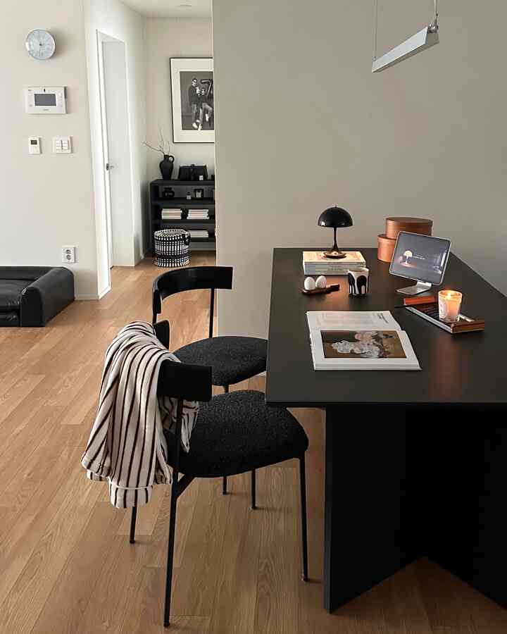 ナチュラルな木目の床とモダンな黒いダイニングテーブル、椅子が配置された洗練された印象のダイニングルーム