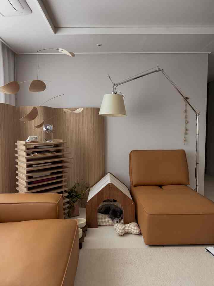 温かみのある木目調とレザーソファが配置されたリビング、ペットハウスとフロアランプが調和する印象的な空間