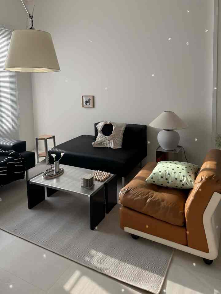 明るいホワイトとナチュラルブラウンのトーンのリビング、モダンなレザーソファとステンレスのコーヒーテーブルが配置された雰囲気のあるインテリア