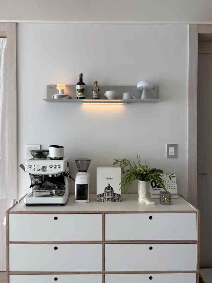 Bright white toned kitchen space featuring a minimalist home cafe setup with coffee machine and grinder atop a spacious dresser
