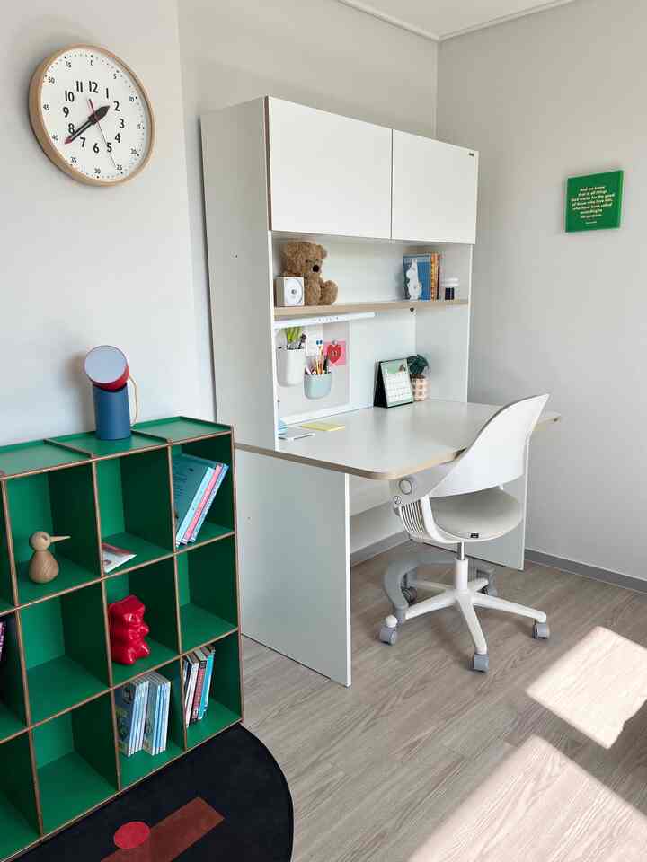 白と緑の調和が取れた子供部屋、シンプルな机とグリーンの本棚が配置された清潔感のある学習空間