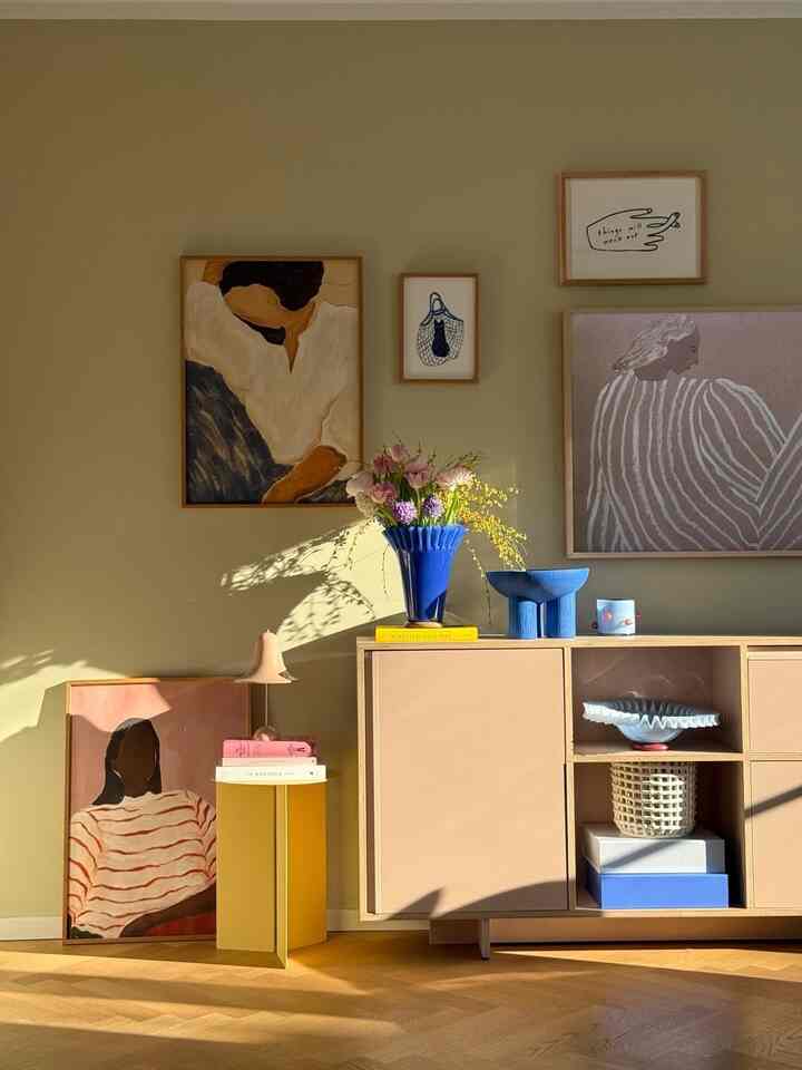 A naturally toned living room featuring pastel furniture and diverse framed artworks creating a bright harmonious space