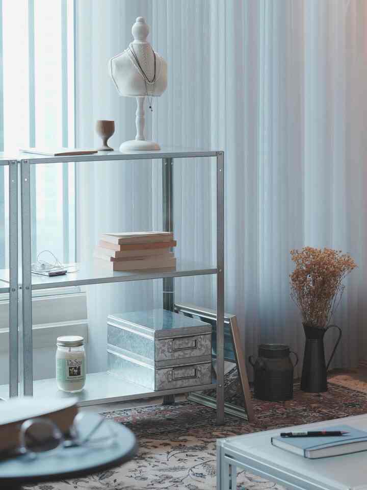 白とグレーの色調のリビングルーム、金属製の棚とヴィンテージの小物が調和した落ち着いた雰囲気のインテリア