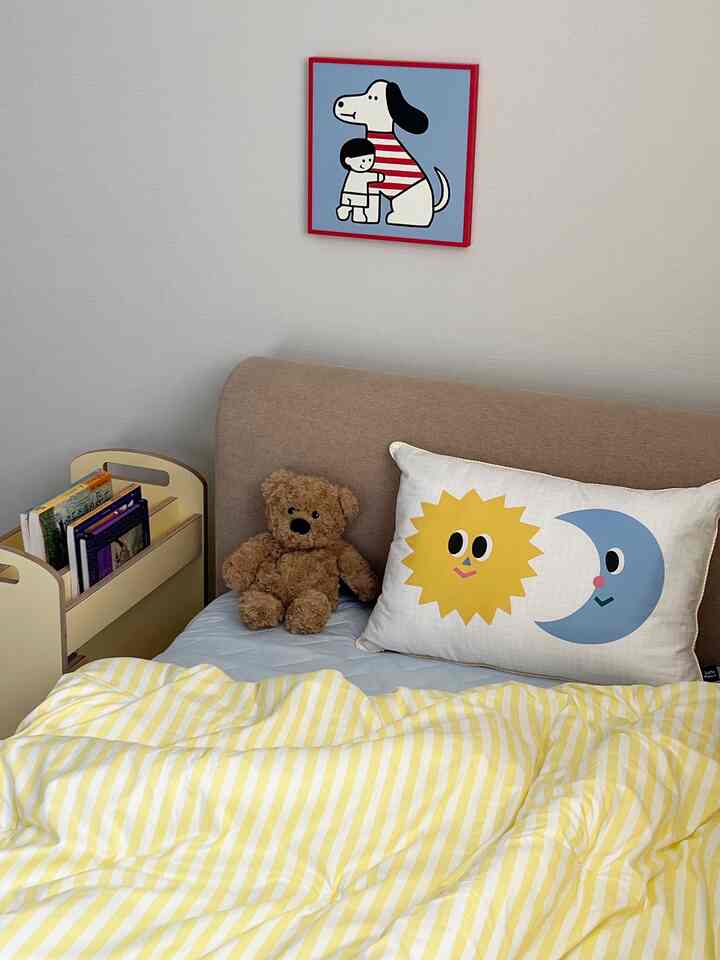 黄色のストライプ寝具とベージュのベッドが配置されたかわいい子供部屋