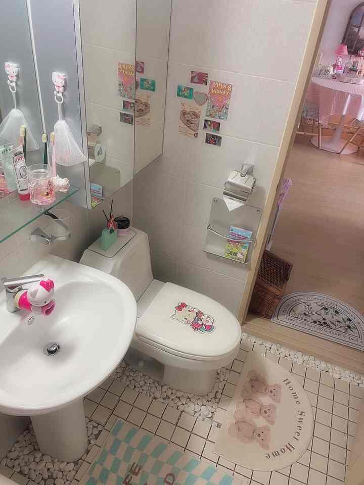 白とベージュのトーンのバスルーム、ハローキティの小物とバスマットが配置されたかわいい雰囲気のあるインテリア