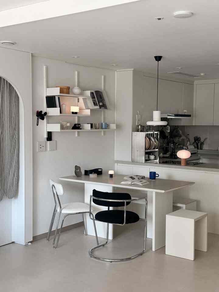 ホワイトとブラックのトーンのキッチンとダイニングスペースで、シンプルでミニマルなダイニングテーブルとチェアが配置された雰囲気のあるインテリア