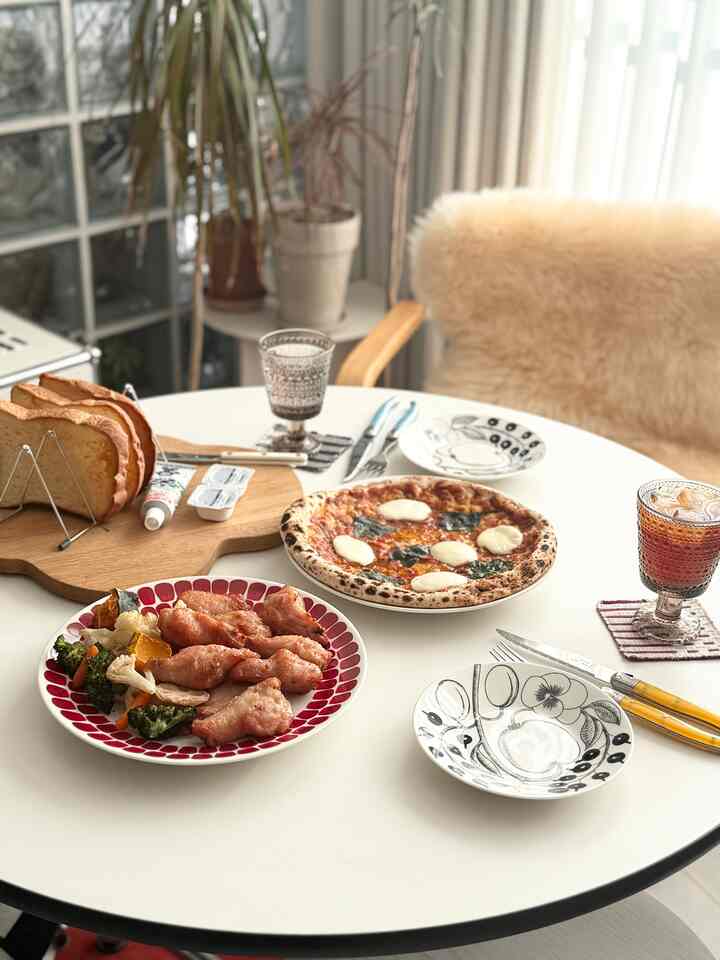 北欧デザインの食器と料理が配置された白い丸テーブルの明るく温かみのあるダイニングルーム