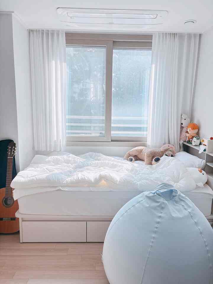 白とナチュラルカラーの子供部屋、収納付きベッドとブルーのビーズクッション、かわいいぬいぐるみが置かれた暖かい雰囲気のあるインテリア