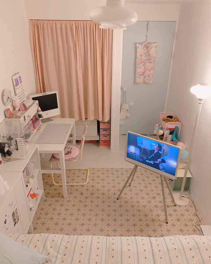 白とピンクのトーンの小さな子供部屋、デスクとテレビ、ラグが配置された雰囲気のあるインテリア