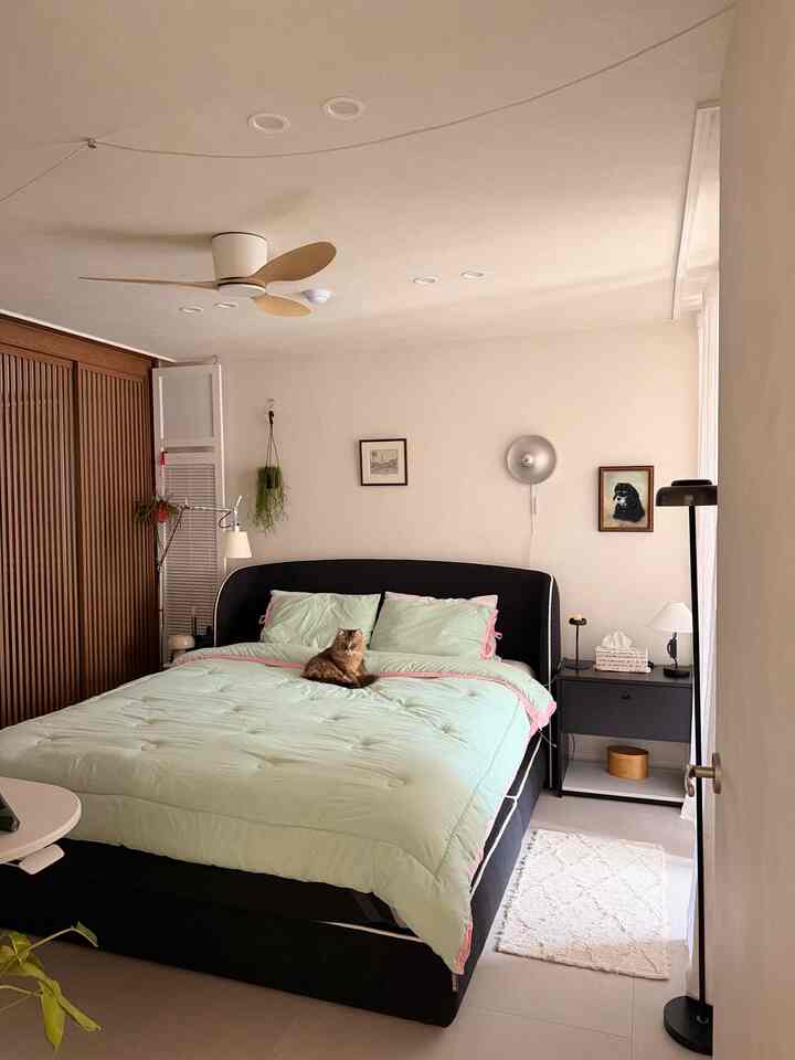 柔らかなミント色の寝具とブラックベッドフレームが配置されたナチュラルな雰囲気の寝室