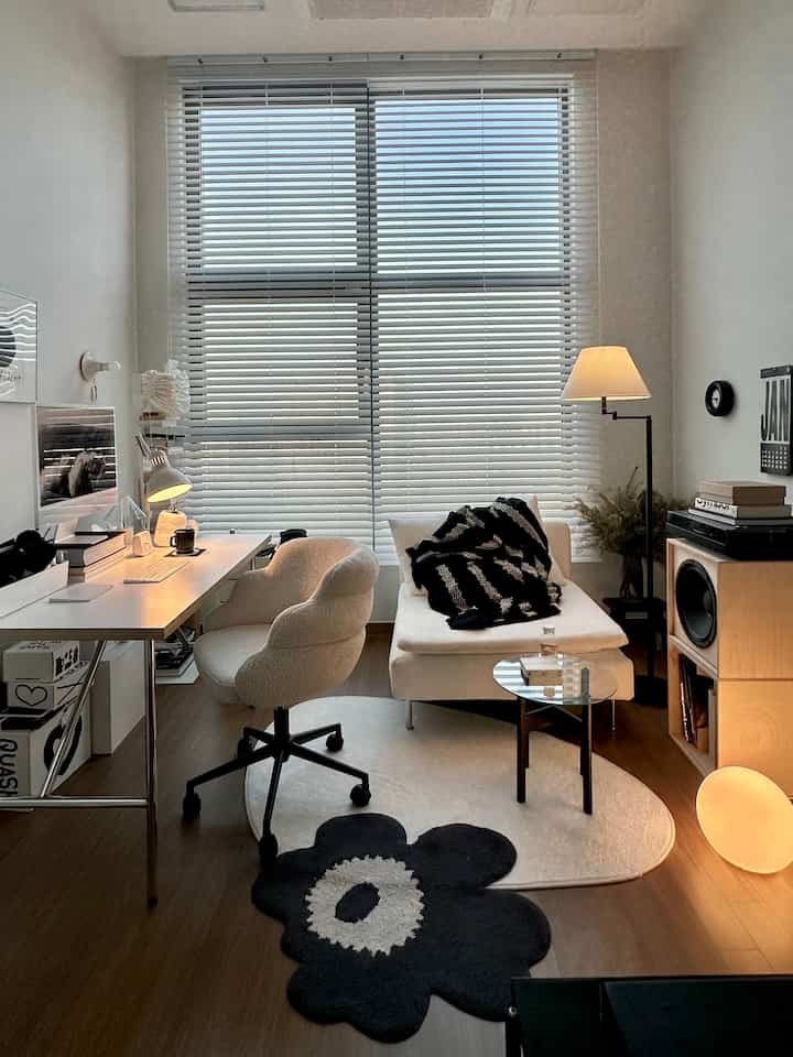 White and natural wood tone studio home office featuring cozy sofa and floor lamp, creating a warm mid-century modern atmosphere