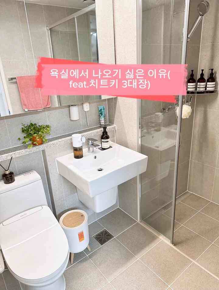 グレーのタイルの壁と床、ホワイトの洗面台とトイレが中央に配置された清潔感のあるバスルーム