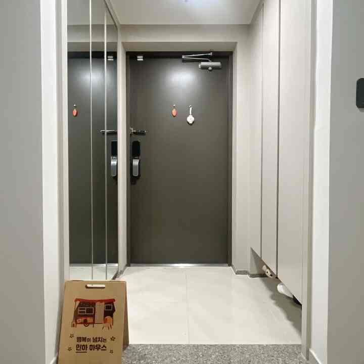 グレーのドアと鏡、白い収納が配置されたモダンで清潔感のある玄関スペース