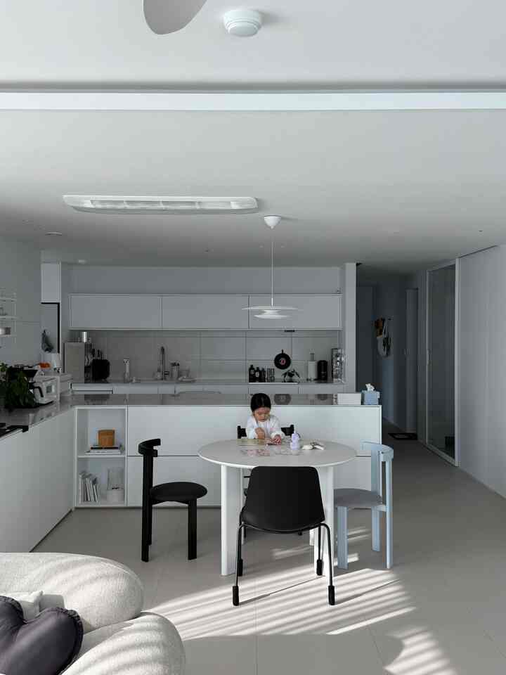 白とモノトーン調のキッチンダイニング、テーブルで遊ぶ子供がいる雰囲気のある空間