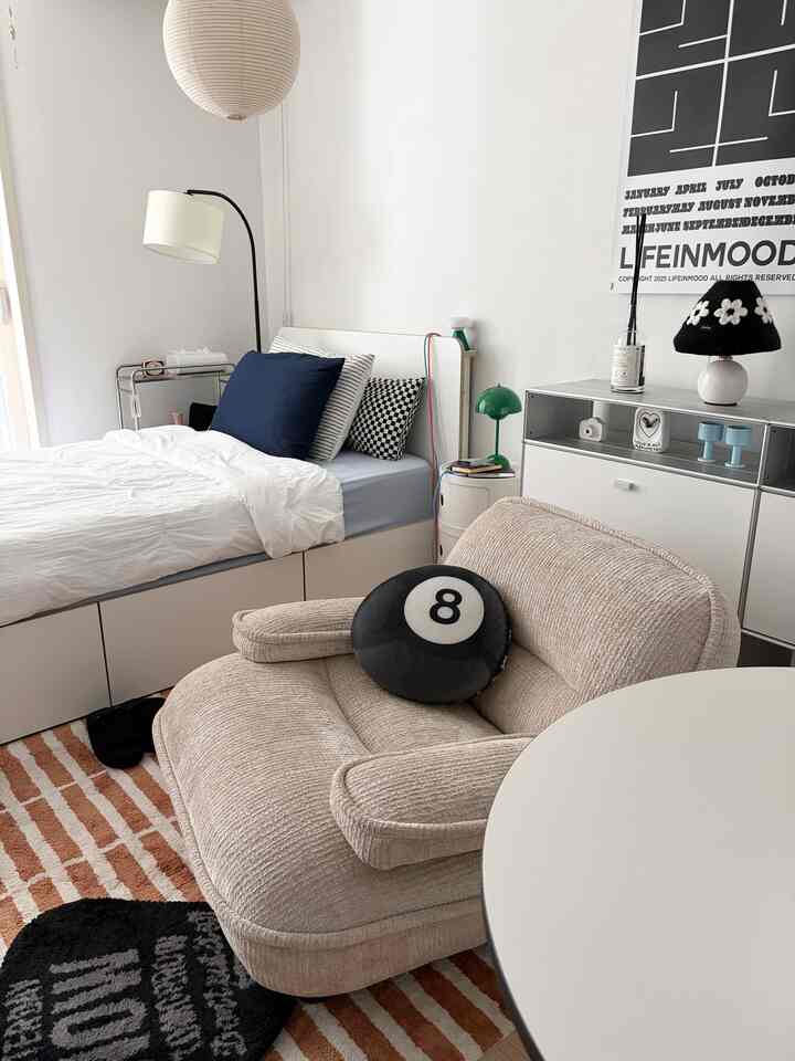 ホワイトとベージュの落ち着いた色調の狭い一人暮らしの寝室、コンパクトなソファとベッドが配置されたモダンな雰囲気のインテリア