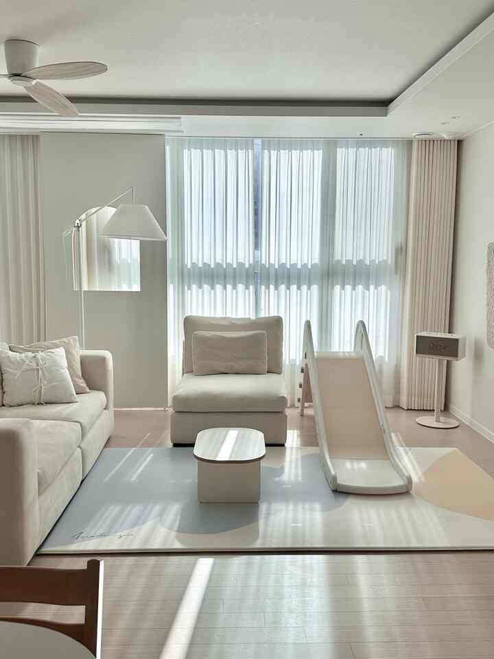 明るいナチュラルトーンのリビング、白いソファと赤ちゃん用滑り台が配置された居心地の良い空間