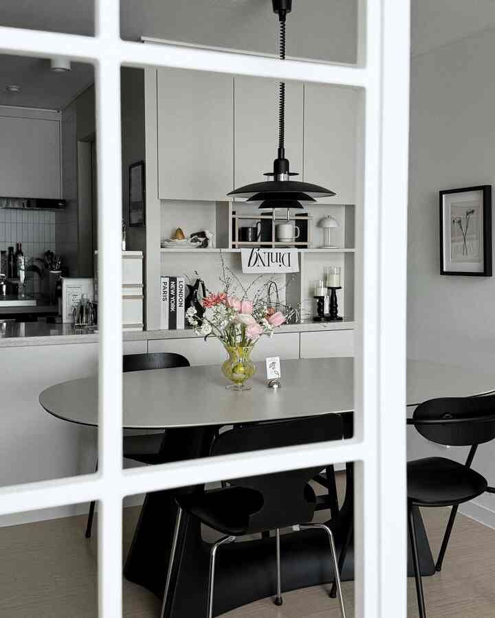 白と黒の調和が取れたモダンなダイニングルーム、セラミックのダイニングテーブルとペンダントライトが配置された空間