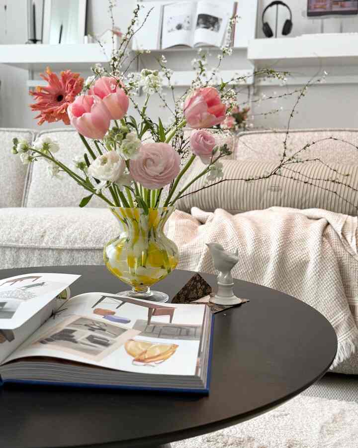 明るいホワイトとベージュのダイニングルーム、中央のテーブルに花瓶と本が置かれ、落ち着いた雰囲気のインテリア