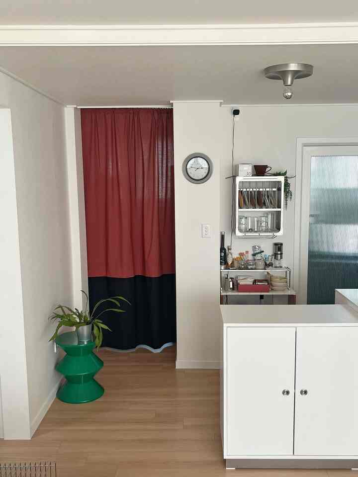 ブリックとブラックのカーテン、白いキッチン家具が配置された明るくすっきりとした廊下キッチンのインテリア