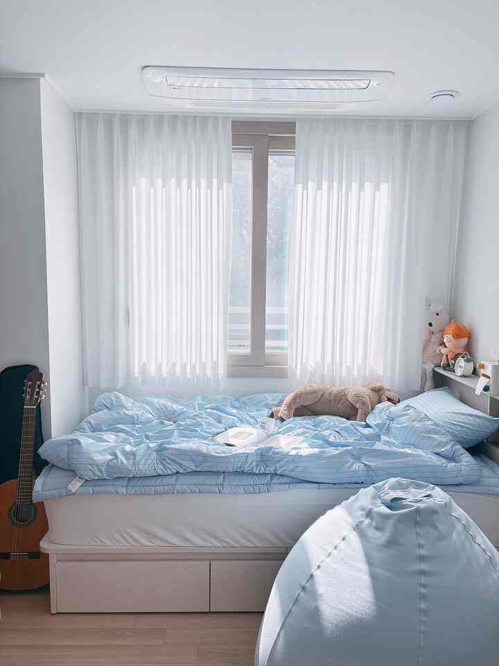 白を基調とした壁とカーテン、青い寝具とビーズクッションが置かれた一人用の寝室